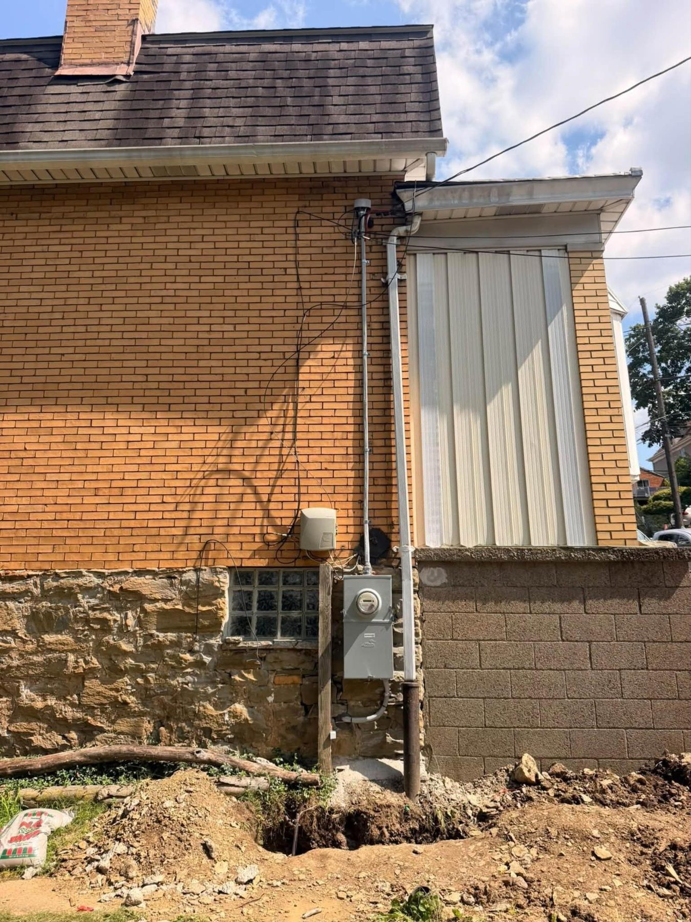 A brick house with a new service mast, meter and disconnect on the outside wall