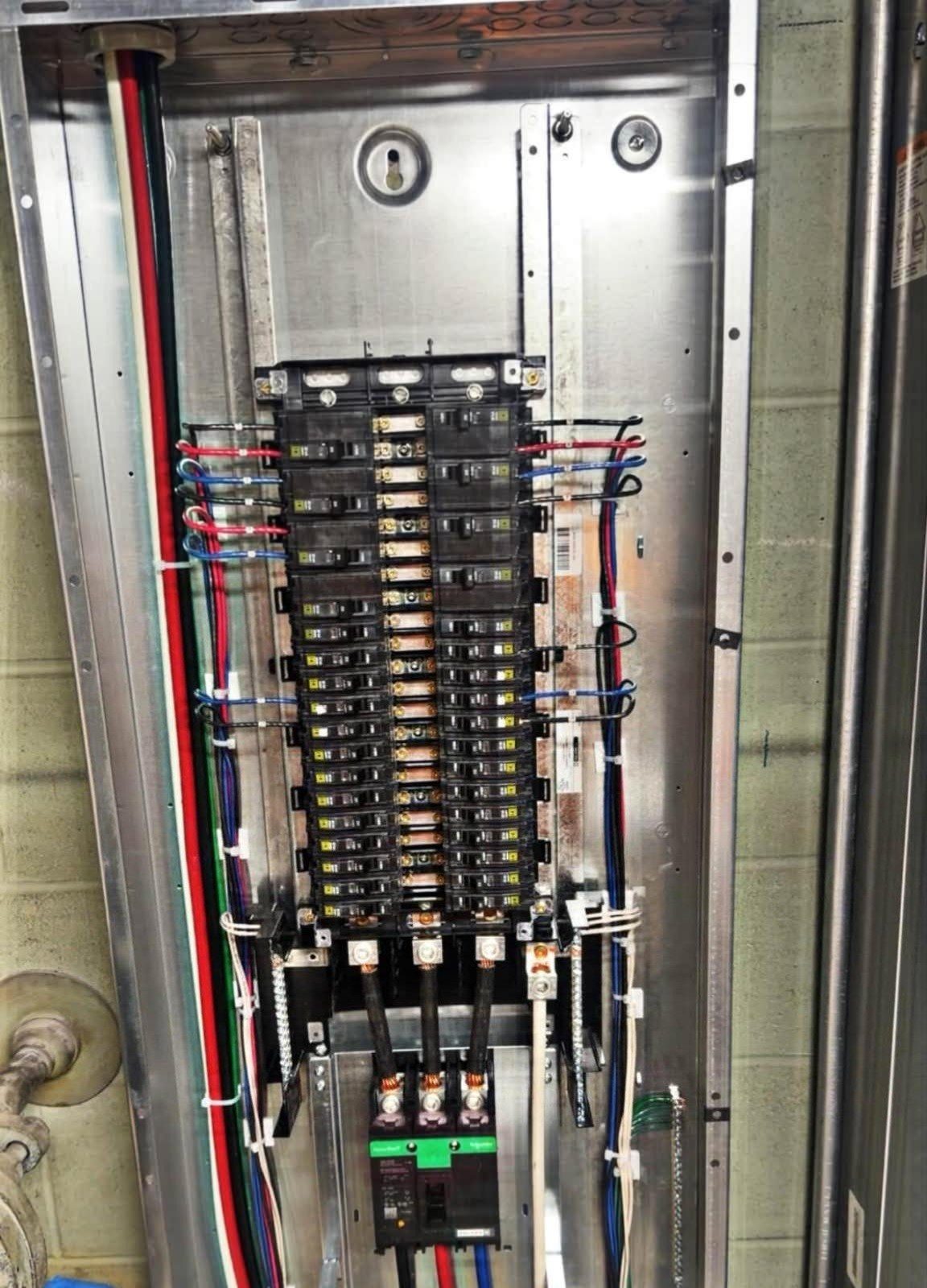 Inside an electrical panel: red, blue and black wires neatly dressed to rows of breakers